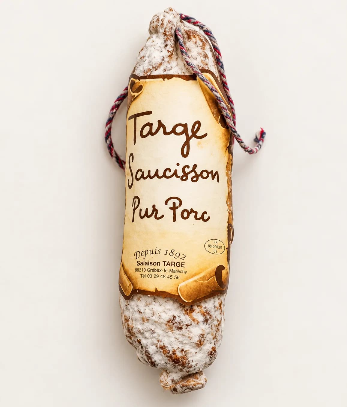 Charcutière souriante dans son séchoir, saucissons suspendus derrière elle